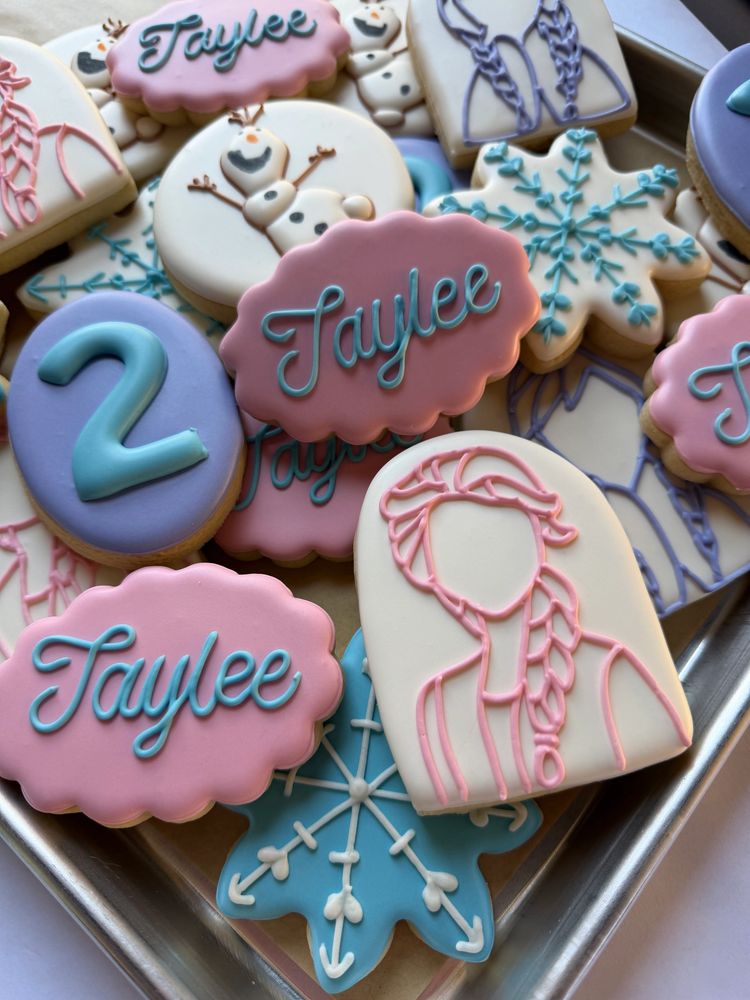 Pink and blue character cookies with snowflakes, braids, and a snowman