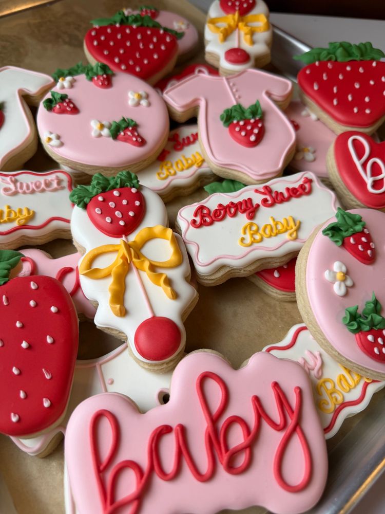 Pink baby shower cookies covered in strawberries, bows, and onesies