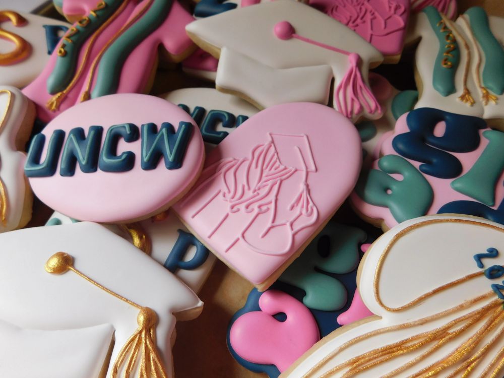Pink, teal, and navy graduation cookies with caps and tassels