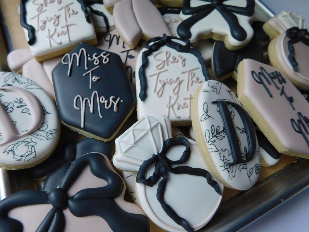 Black, blush, and ivory wedding cookies with bows, rings, and monograms