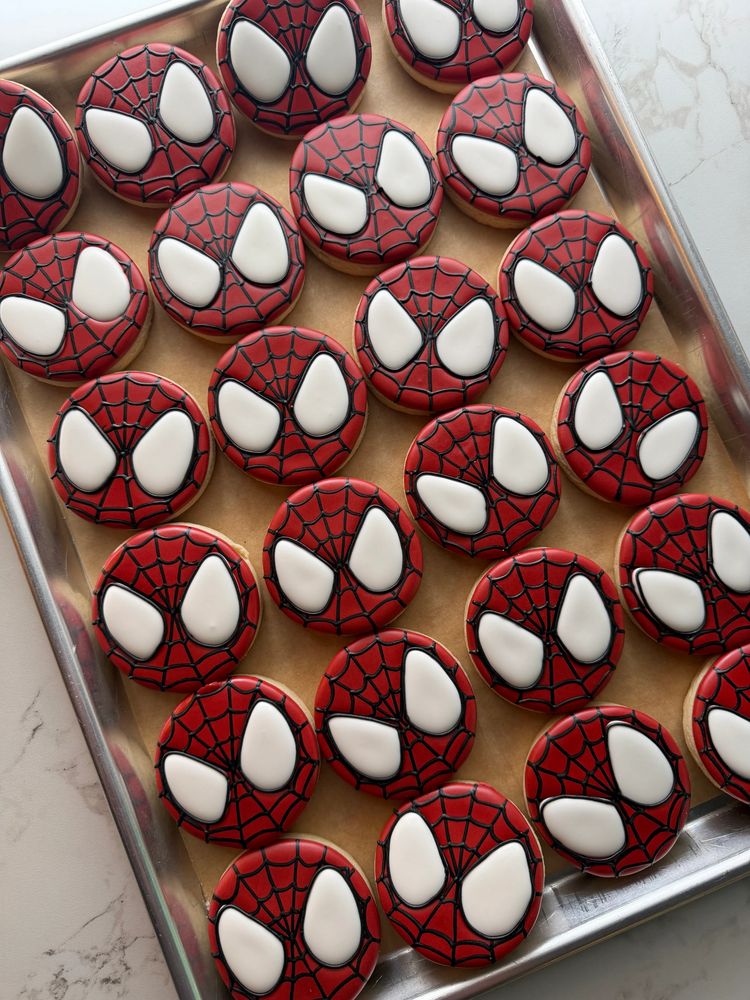 A tray of round red-and-white character mask cookies with black piping
