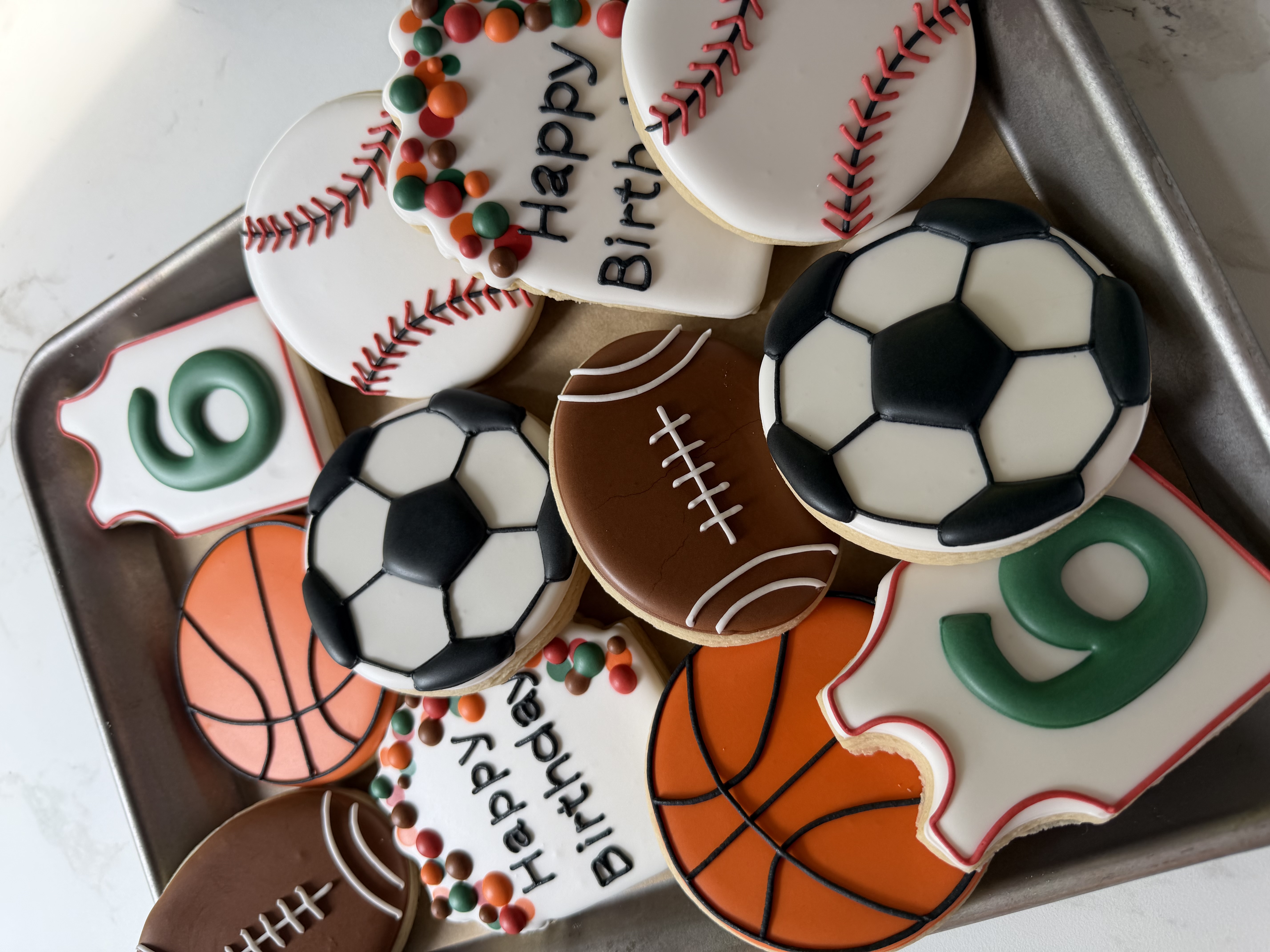 Sixth-birthday sports cookies shaped like basketballs, soccer balls, footballs, baseballs, and jerseys