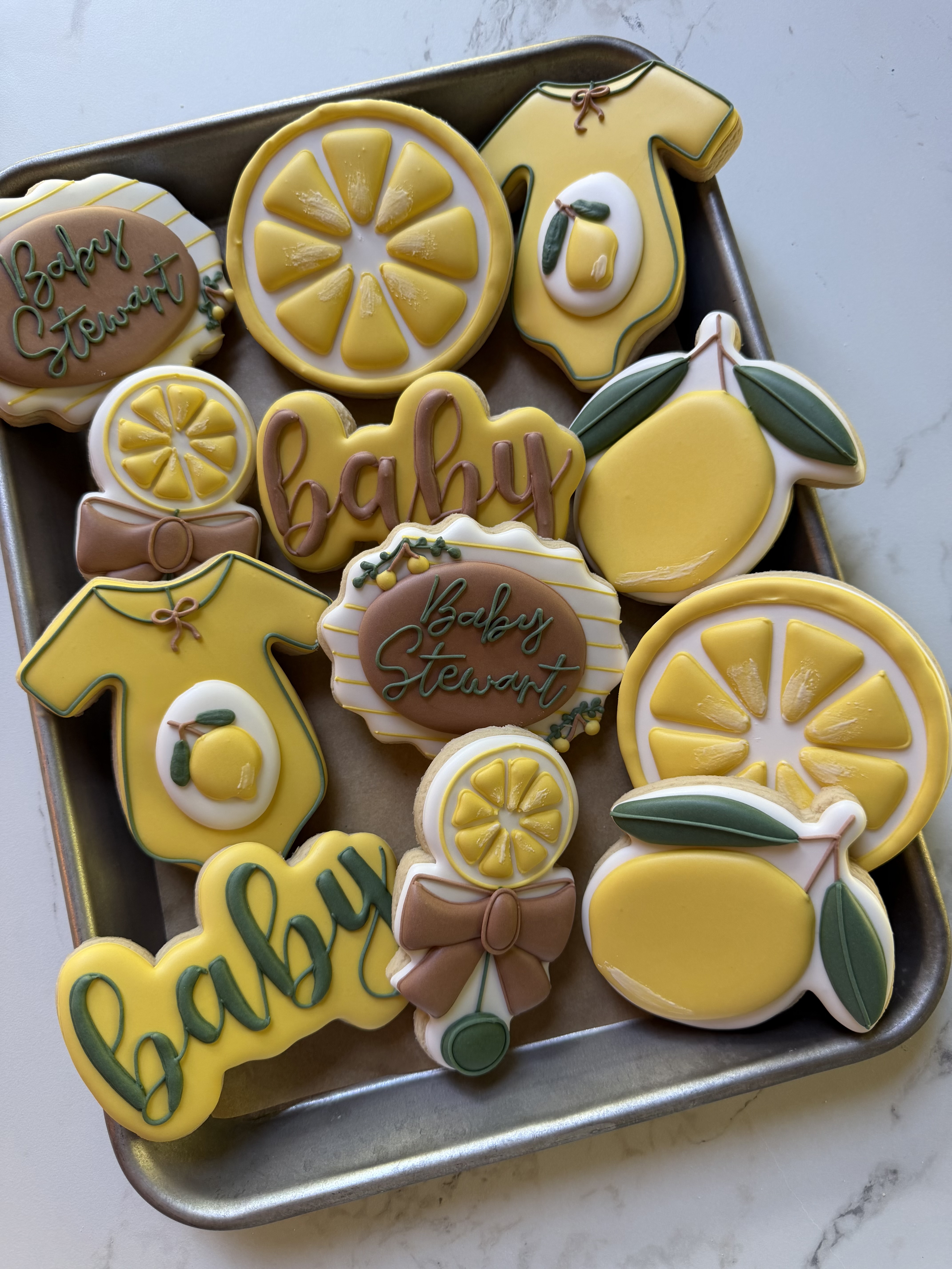 Lemon baby-shower cookies with onesies, bows, and Baby Stewart plaques