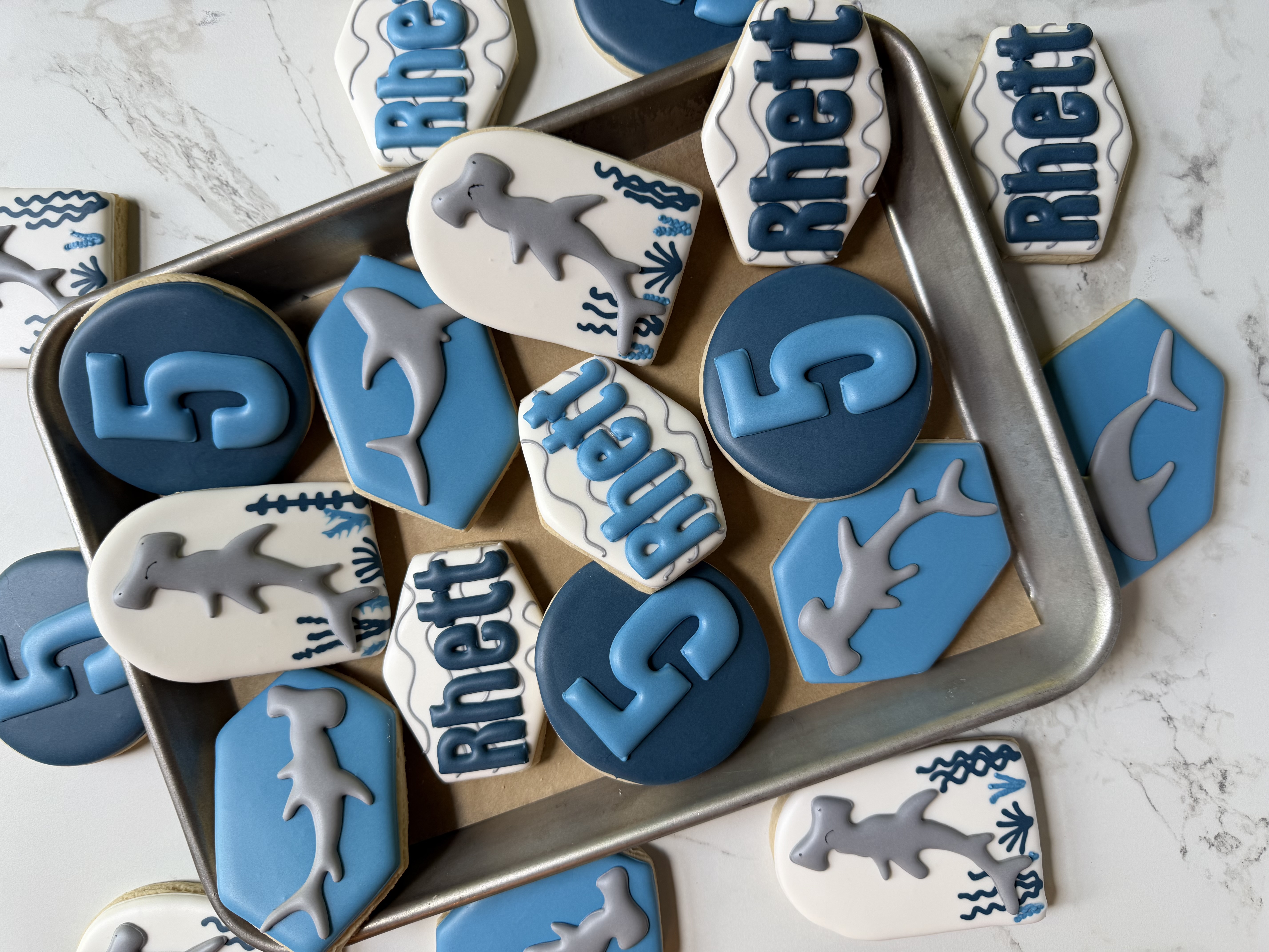 Blue fifth-birthday cookies with hammerhead sharks and the name Rhett