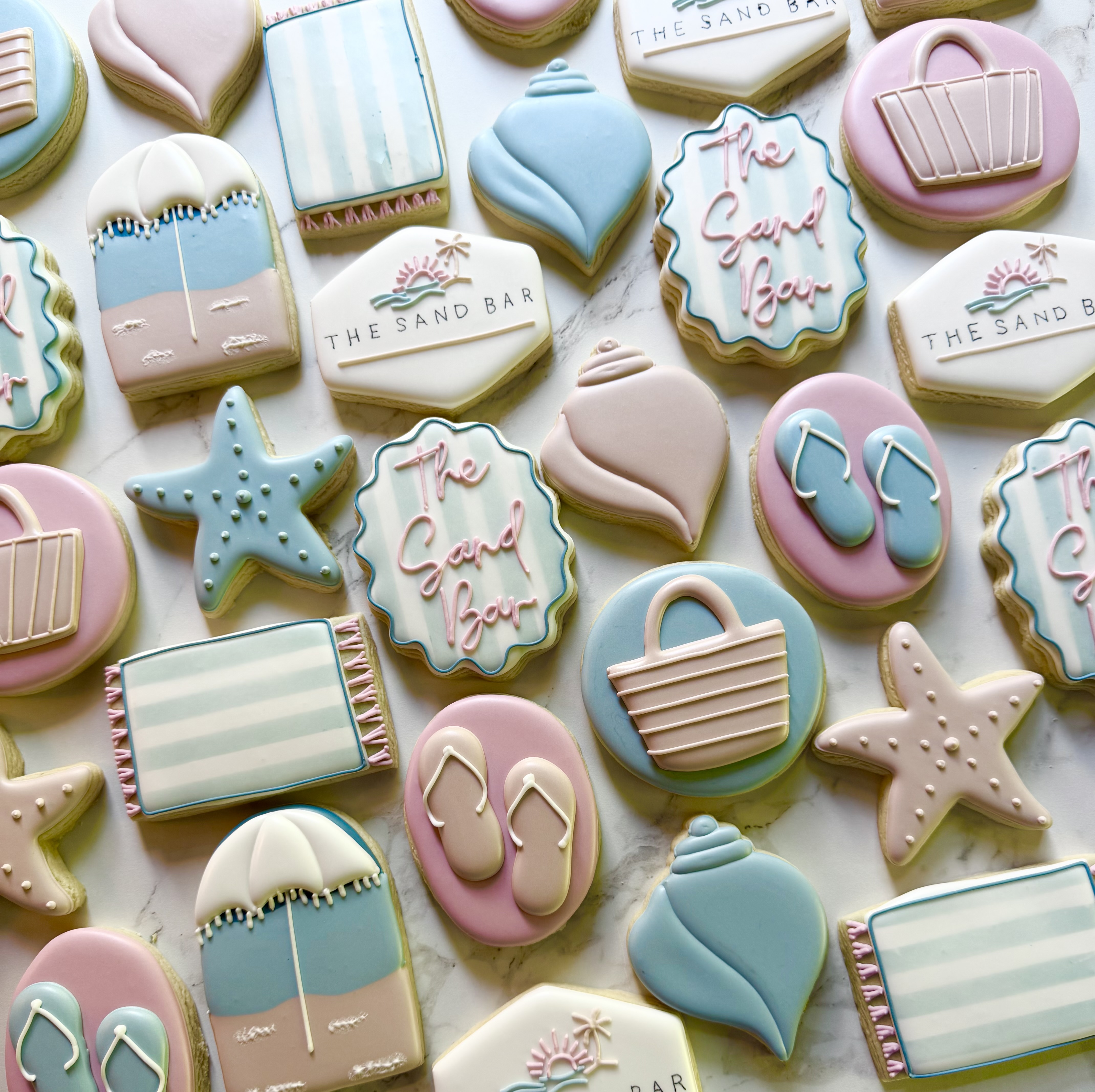Beach cookies with shells, flip-flops, starfish, and The Sand Bar lettering in pink and blue